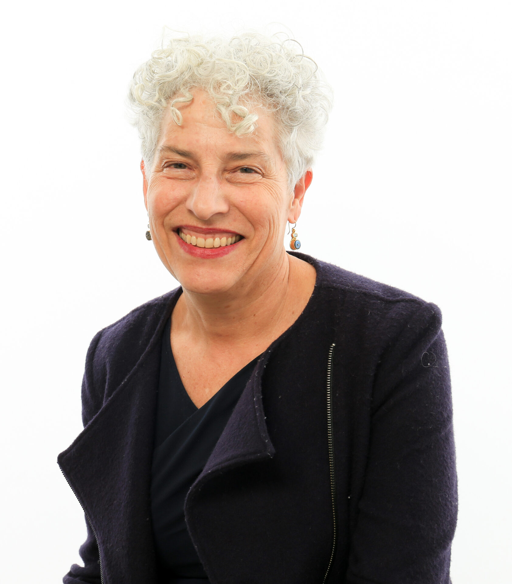 A woman with white hair is smiling for the camera.